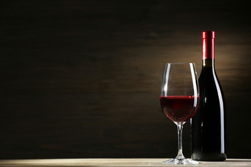 Wineglass and bottle on wooden background