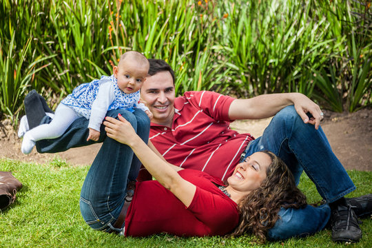 Pareja joven disfrutando de un hermoso d&iacute;a de sol con su bebita en un parque