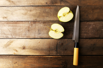 Sliced apple with knife on wooden background