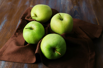 Green apples on wooden table with napkin, closeup