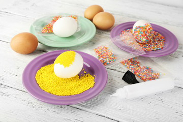 Decorating Easter eggs on color plate on wooden table, closeup