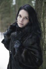 Girl wearing a fur coat in winter forest