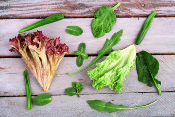 Variety of green leaves for salad, on wooden table