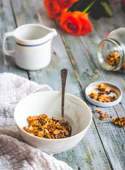 granola with honey, nuts and dried fruits in white piala, flower