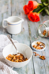 granola with honey, nuts and dried fruits in white piala, flower