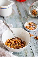 granola with honey, nuts and dried fruits in white piala, flower