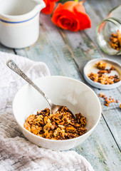 granola with honey, nuts and dried fruits in white piala, flower