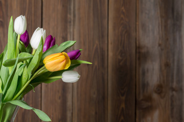 Colorful tulips in a vase on a wooden table