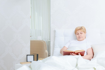 Obraz na płótnie Canvas Woman reads a book in bed