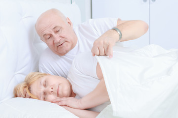 Elderly couple asleep in bed