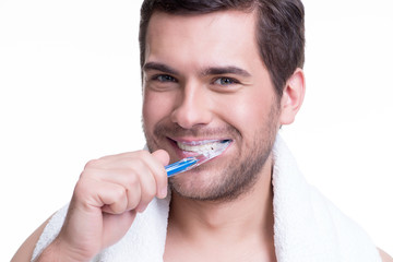 Happy young man brushing teeth.