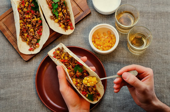 Man holding tacos with meat, corn