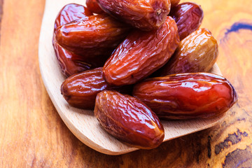 dried dates on spoon wooden background