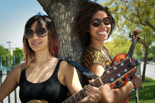 Female guitarist and violinist smiling outdoors