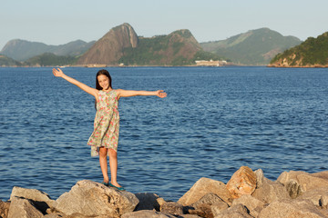 Happy smiling beautiful teen girl standing on stones 