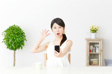 スマートフォンを持って驚く女性