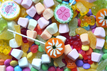 Candy, lollipop, colored smarties and gummy bears background
