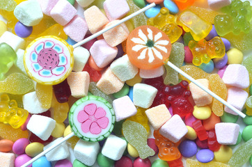 Candy, lollipop, colored smarties and gummy bears background