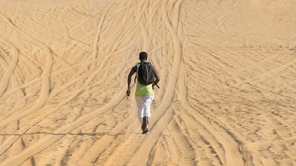 Man seen by back and running on a sand road