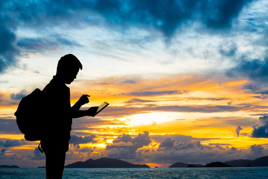 Silhouette man with digital tablet in hands at sunset beach