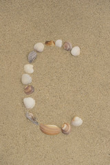 Fototapeta na wymiar Buchstabe C aus Muscheln im Sand