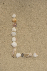 Buchstabe L aus Muscheln im Sand