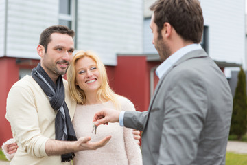 Real estate agent delivers keys to young atractive couple