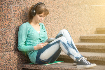 Beautiful young woman student with note pad and headphones