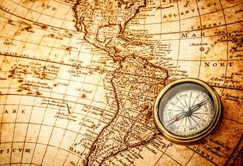 Naklejka na ściany i meble Vintage compass lies on an ancient world map.