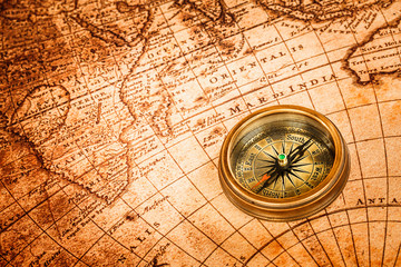 Obraz na płótnie Canvas Vintage compass lies on an ancient world map.