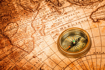 Plakat Vintage compass lies on an ancient world map.