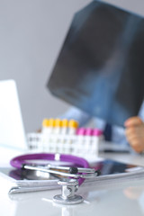 Medical doctor  sitting at table and looking patients roentgen