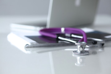 Violet stethoscope near laptop computer