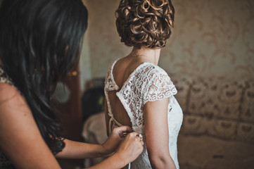 The girlfriend helps the bride to dress a wedding dress 2298.