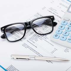 Calculator with pen, glasses and utility bill - close up shot