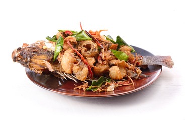 Fried fish with herbs on white table