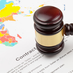 Wooden judge's gavel over world map and contract - close up shot