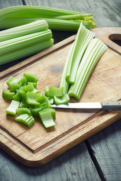 Fresh green celery stems on wooden cutting board closeup