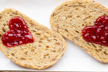 Grain slice of bread with jam heart shape.