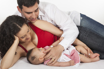 Padres jóvenes recostados con su pequeña bebé de cuatro meses