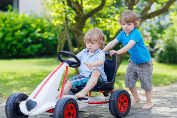 Two happy sibling boys having fun with toy car