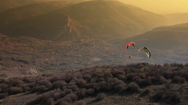 Paraglider Soaring Over The Mountains during sunset
