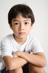 Little asian boy sitting with small smile