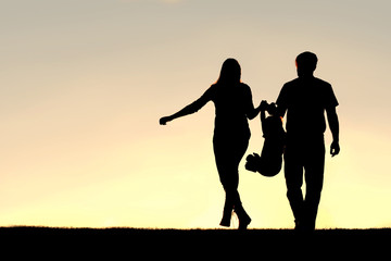 Fototapeta na wymiar Silhouette of Family of Three People Walking at Sunset