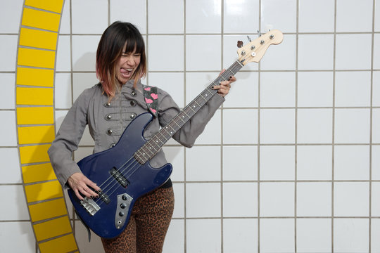 Female Musician Playing Guitar In Subway With Tongue Out