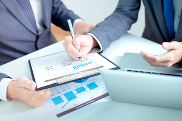 Two businessmen looking at report and having a discussion in off