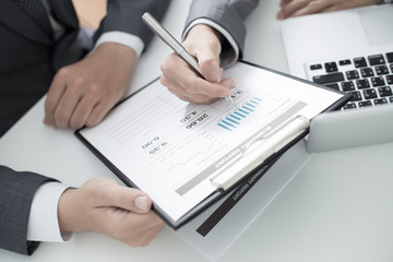 Two businessmen looking at report and having a discussion in off