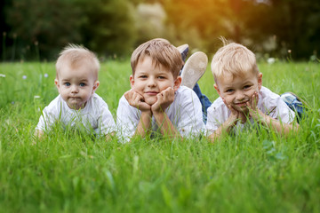 Three happy children brothers  resting on the green grass in s
