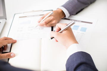 Two businessmen looking at report and having a discussion in off