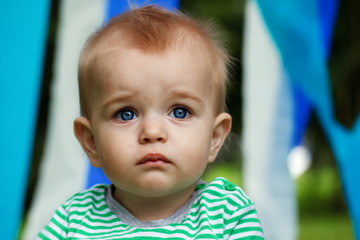 Serious little boy portrait with big opened  eyes on a blue and